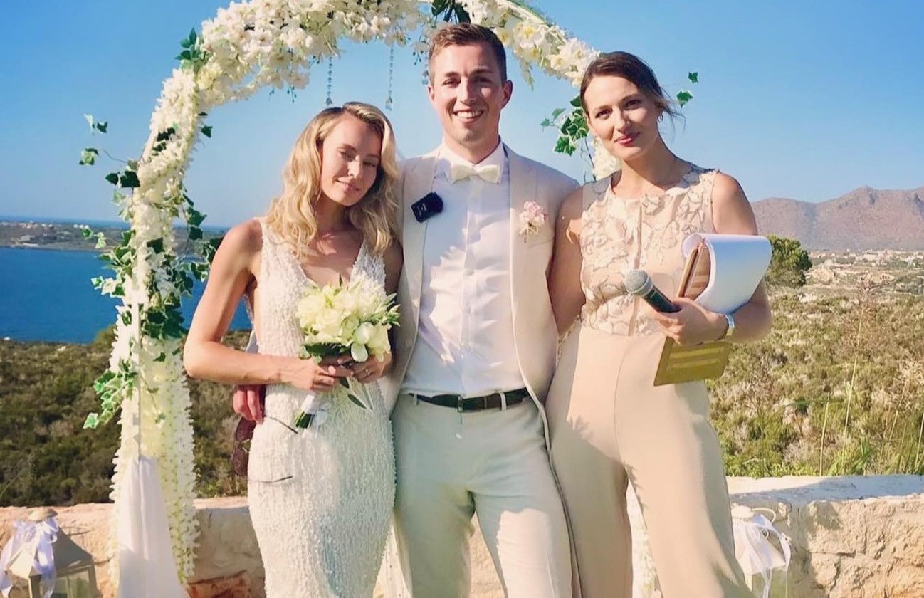 Wedding photo against the backdrop of an arch and the sea with a host